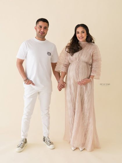 A full-length portrait of an elegant couple during their maternity session. Their coordinated white and neutral outfits create a clean, classic look.