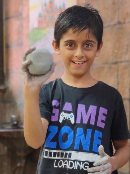 Ready to create. This young student holds a ball of clay, the starting point for any pottery project. We teach them how to prepare the clay and turn it into whatever they can imagine.