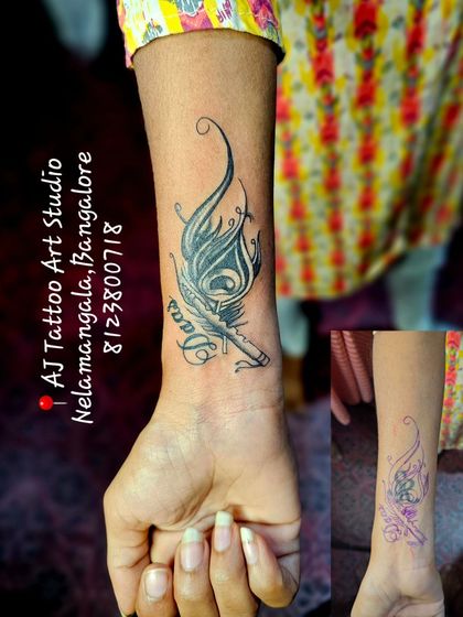 This wrist tattoo was reworked and covered with a new design of a peacock feather and flute.