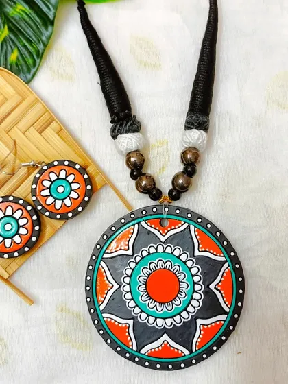 This version of the circular mandala pendant necklace is in a striking orange, teal, and black.