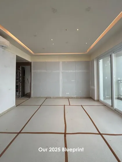 An "in the works" photo of a space with drywall and ceiling light troughs installed. This shows the project at a critical construction phase, where the blueprint begins to take three-dimensional form.