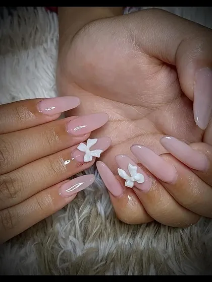 Simple yet elegant nude extensions with 3D white floral accents. This is a great option for clients who want a subtle but beautiful design.