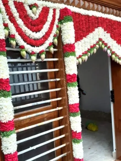 A traditional flower decoration for a home door. The red and white garlands are arranged in a beautiful pattern to welcome guests.