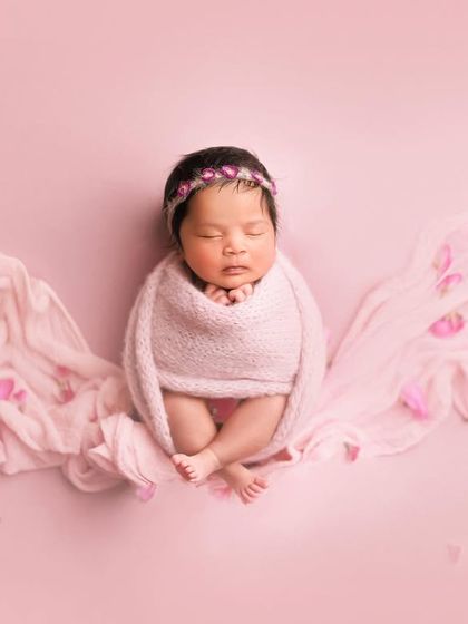 Pretty in pink. This artistic shot uses a flowing pink fabric to create wings, with petals scattered around for a magical, floral effect.