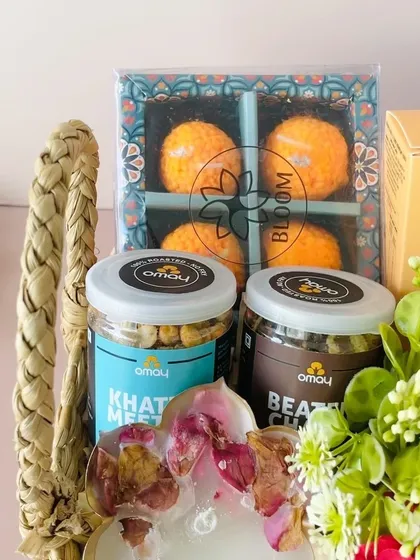 A close-up of the Kauna square basket, showing the delicious Omay snacks and the unique laddoo-shaped candles.