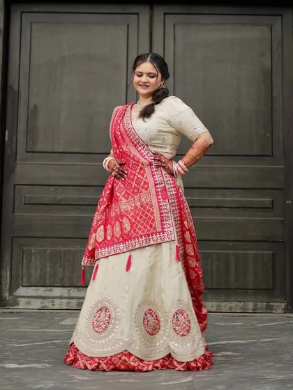 A full-length shot showing the beautiful flow of the ivory and red lehenga. The makeup is designed to complement this elegant and understated bridal style.