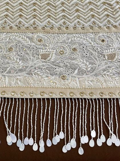 A close-up of the pallu's tassel border, showing the hand-sewn details.