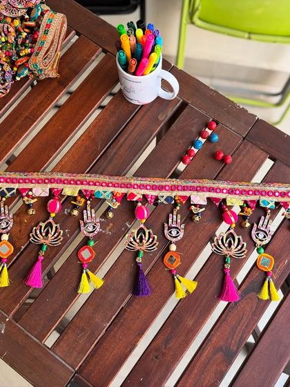 The 'Shubh Toran' on my work table, surrounded by pens and beads. This is where the magic begins.