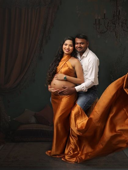 Two hearts, one love, and a little soul on the way. This portrait captures the couple in a classic pose, with a flowing satin drape adding a touch of drama and elegance.