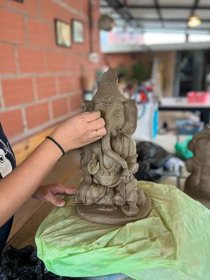A student carefully puts the final touches on her Ganesha idol. It's a moment of pure focus and creativity.