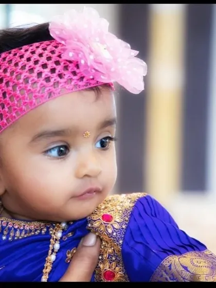 A detailed close-up of the baby girl in her traditional attire, highlighting her delicate features and the beautiful silk fabric of her dress.