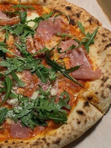 A close-up of my Prosciutto & Arugula pizza. You can see the delicate slices of prosciutto, fresh arugula, and shavings of parmesan on top of the perfectly baked crust.