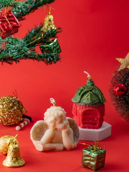 A Christmas-themed figurine candle featuring a sleeping angel and a little house, perfect for creating a peaceful holiday scene.