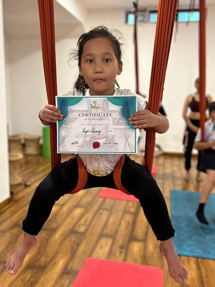 Another happy graduate from our kids' summer yoga workshop, confidently posing in the aerial silk.