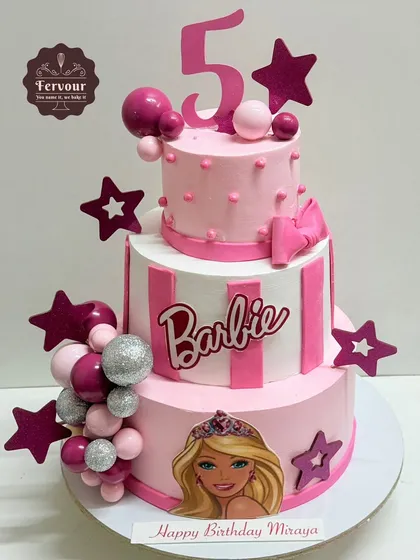 A grand three-tier Barbie theme cake for a 5th birthday celebration. This cake is all about pink, with stripes, stars, and sparkling silver balls, bringing the glamorous world of Barbie to the party.