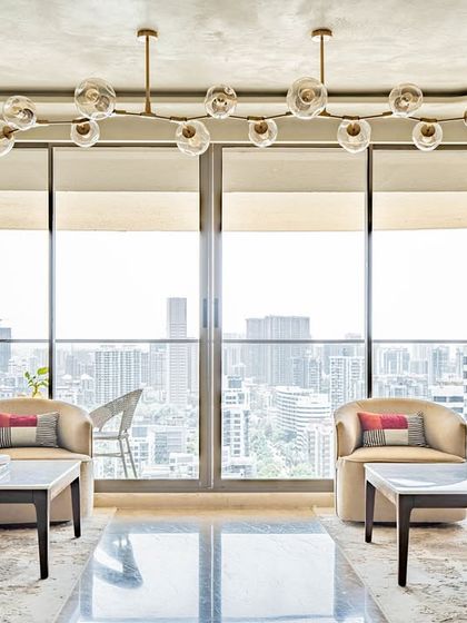 A panoramic view of the 'Eternity' living room, emphasizing the expansive feel and the stunning city views through the floor-to-ceiling windows. The symmetrical layout creates a sense of formal elegance.