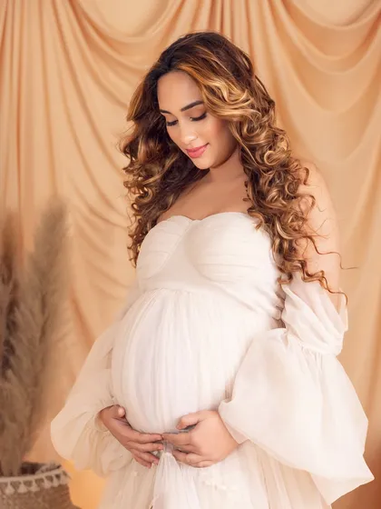 A classic and tender pose, looking down at her baby bump with a heart full of love.