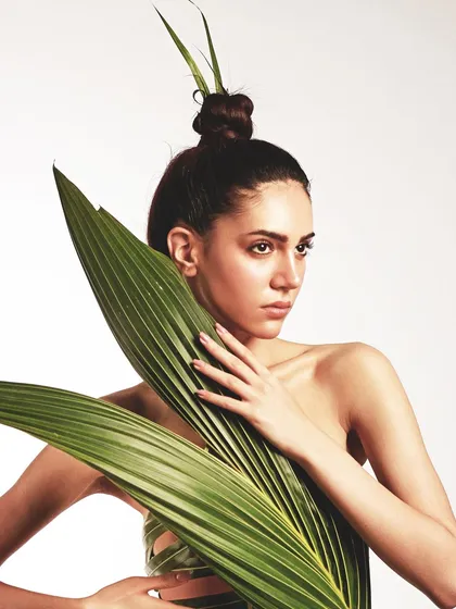 A powerful pose showing the structure of the leaf dress. The hair is pulled up into a sharp top-knot, adding to the architectural feel of the look.