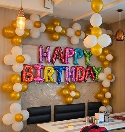 A simple and sweet birthday decoration at a restaurant. We used gold and white balloon clusters and a multi-colored 'Happy Birthday' foil balloon banner to create a festive corner.