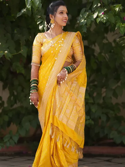 A full-length view of a bride's Haldi look. The yellow silk saree is draped elegantly to allow for movement while maintaining perfect pleats, ideal for ceremony and celebration.