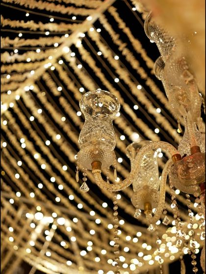 A close-up of a crystal chandelier against the backdrop of the fairy light and floral string canopy. The combination of different light sources created depth and sparkle.