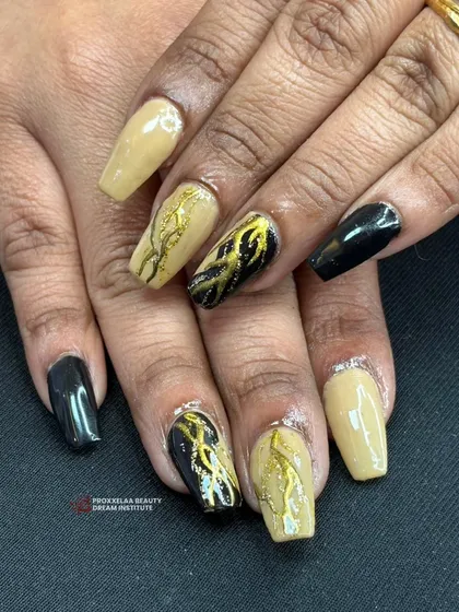 A different angle of the black, tan, and gold textured set, showing the contrast between the glossy and textured finishes on these coffin-shaped nails.