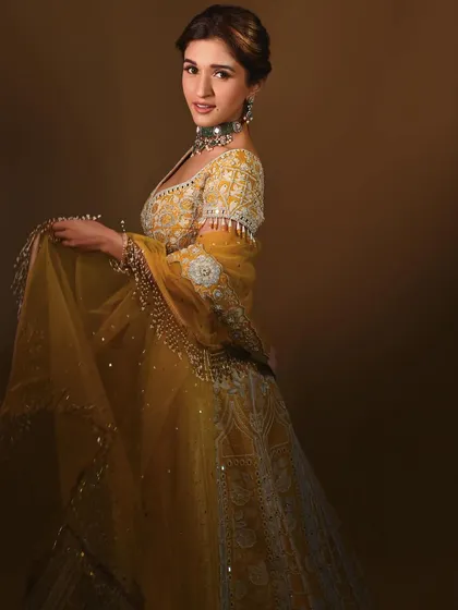 A three-quarter view that captures the flow of the dupatta and the intricate embroidery on the lehenga. The makeup look is soft and romantic.