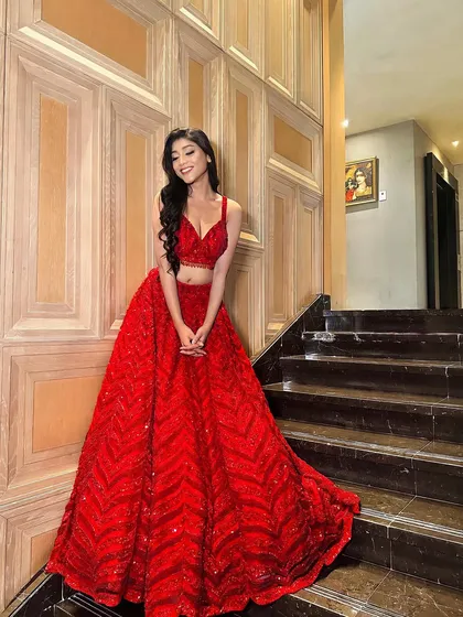 A full-length shot of this dreamy red lehenga. The nude matte eyes and glass skin create a beautiful contrast with the vibrant, sparkling outfit.