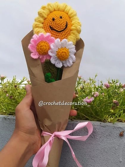 A lovely custom bouquet featuring a smiley sunflower and two daisies in pink and white. This arrangement is perfect for sending a message of happiness and cheer.