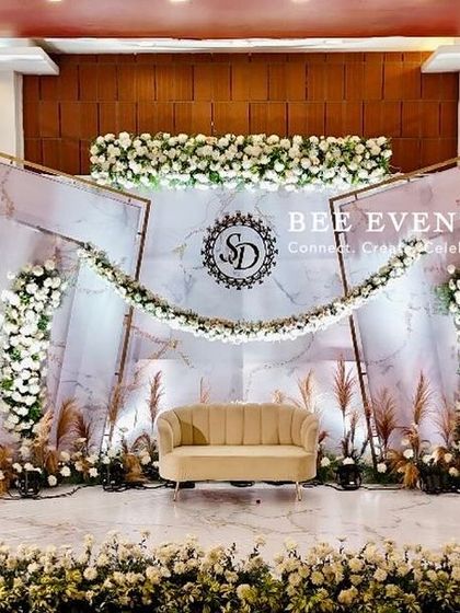 A full view of the elegant white and gold reception stage. The design's clean lines, custom monogram, and lush floral arrangements create a sophisticated and timeless look that impresses from every angle.