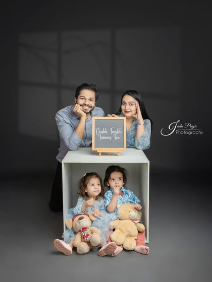 A beautifully composed family portrait with the parents framing the shot and the twins nestled in the box below. This is a great example of a modern family photo.