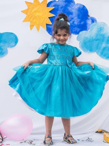 A full view of this stunning turquoise tulle dress. The design is all about movement and grace, making it a beautiful choice for any little girl who loves to twirl.