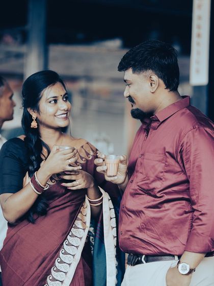 A candid moment of a couple sharing a cup of tea at a market, their traditional attire and the setting creating a warm, retro feel.
