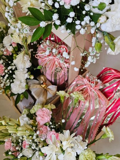 An overhead view of a wedding hamper, showcasing how I balance beautifully wrapped gifts with lush floral arrangements. The mix of pinks, reds, and whites creates a vibrant and joyful presentation.
