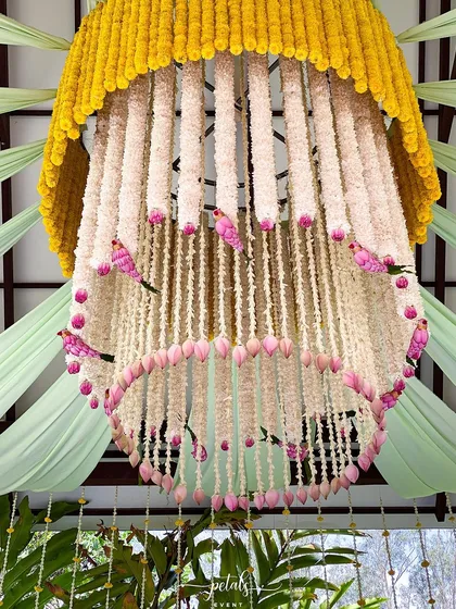 My bespoke floral designs are a signature touch. This custom chandelier, crafted from strings of tuberose and marigolds with delicate lotus buds and whimsical pink birds, became a stunning centerpiece that captured the couple's unique style.