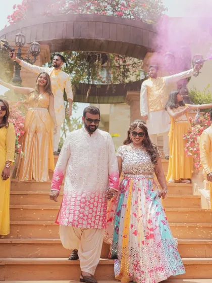 A fun-filled moment at a pastel-themed Haldi, with the couple and their friends celebrating with colorful smoke bombs.