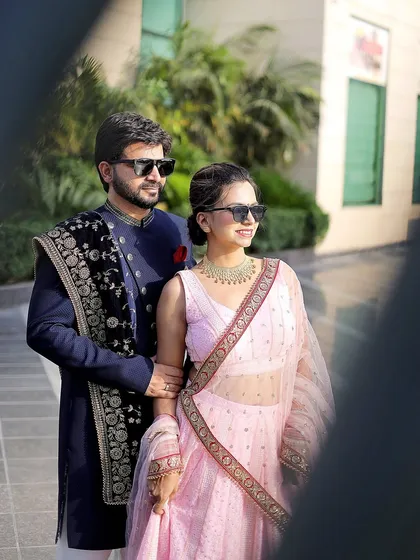 A cool and stylish pre-wedding portrait. The sunglasses add a modern touch to the couple's traditional outfits, showing off their fun personality.