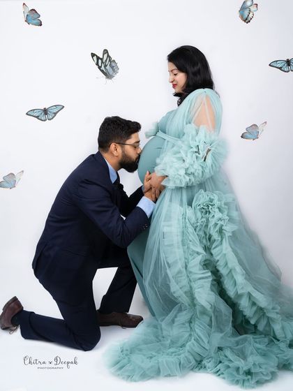 A magical kiss for the baby, surrounded by whimsical butterflies. This is a beautiful and creative concept for a couple's shoot.