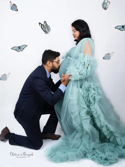 A magical kiss for the baby, surrounded by whimsical butterflies. This is a beautiful and creative concept for a couple's shoot.