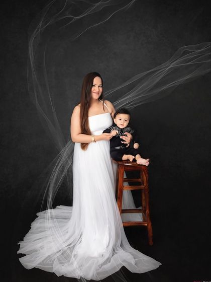 A stunning mother and son portrait. The flowing white gown and dark background create a dramatic and beautiful image.