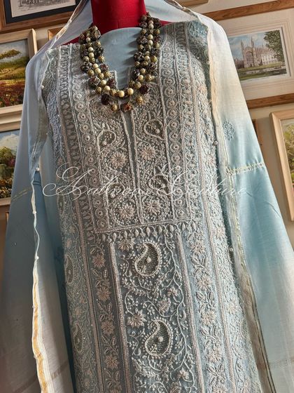 An elegant powder blue silk chanderi suit, heavily embellished with Kutdana, sequins, and seed pearls. The ombré dupatta adds a touch of modern grace.