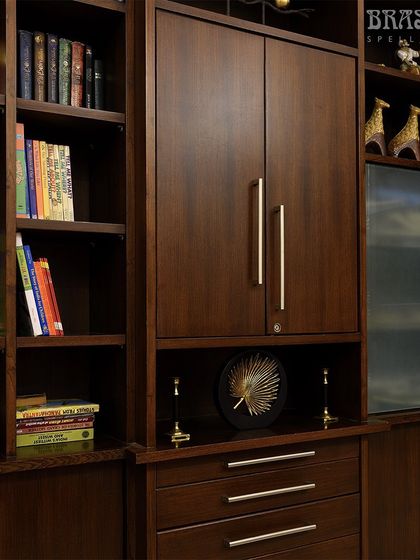 A wider view of the library, showing how the Norton handles provide a sleek, contemporary accent to the extensive dark wood shelving.