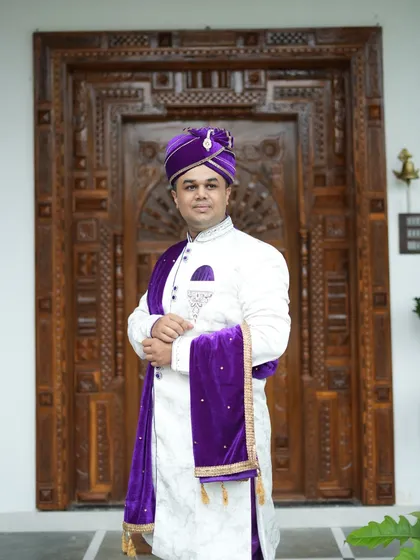 A closer look at the fine details on our white and purple sherwani set. The rich velvet stole and the perfectly tied pheta add a touch of royalty to this rental outfit.