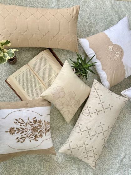An artfully arranged collection of our beige and white embroidered cushions. Each piece features a unique design, from classic floral motifs to modern geometric patterns, showcasing the breadth of our artisanal craftsmanship.