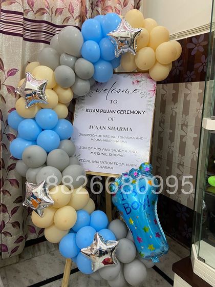 A full view of the Kuan Pujan welcome stand, featuring a personalized sign with the baby's name and ceremony details, framed by a balloon arrangement.