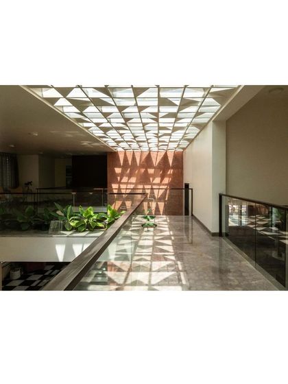 The geometric skylight in the Notan Home creates a captivating pattern of light and shadow along the upper-level corridor, turning a simple passageway into a visual experience.