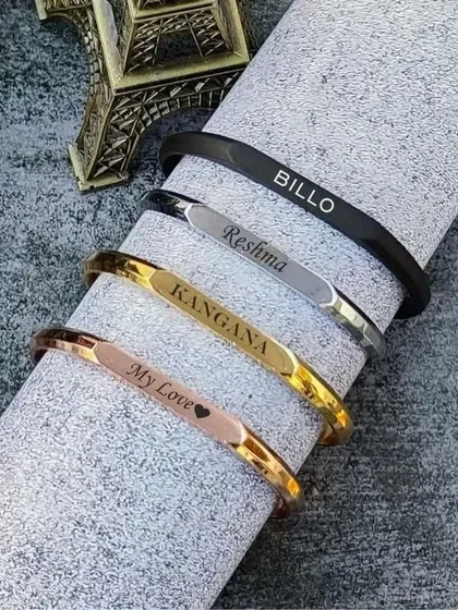 I offer these sleek name bracelets, or kadas, in a variety of finishes to match any style. This image shows the range, including rose gold, classic gold, silver, and modern matte black, each engraved with a name.