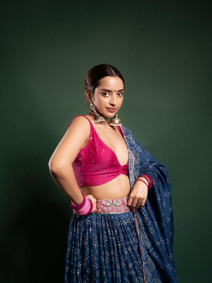 A close-up shot focusing on the details of the blouse and the 'kamarbandh'. The model's pose highlights the craftsmanship of the festive attire.