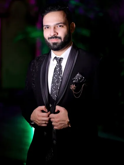 A confident portrait of the groom in his three-piece suit. The lighting highlights the texture of his jacket and his sharp look.