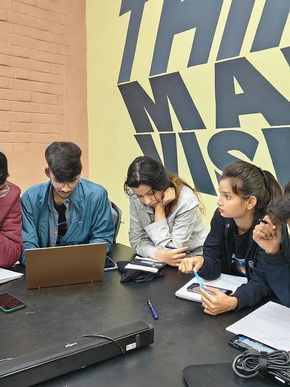 A small group of students collaborating around a laptop. Peer-to-peer learning is a vital part of my workshops, as it mirrors the teamwork required in a professional design studio.